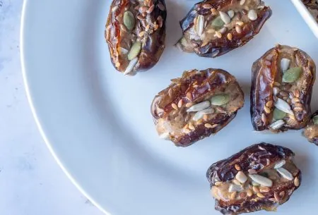 Plate spread with eight dates, stuffed full with nut butter and mixed seeds