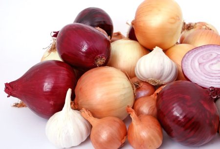 A mixture of brown and white onions and garlic bulbs