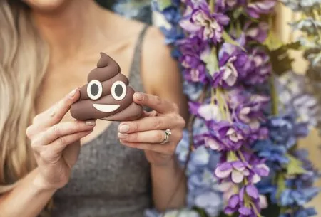 A woman's hand holding a poo emoji model