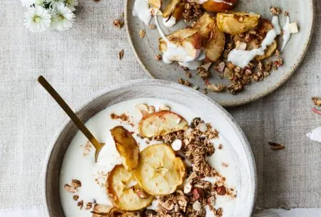 A bowl of yogurt with granola and dried apple and another plate with dried apple and granola and a sprinkle of yogurt