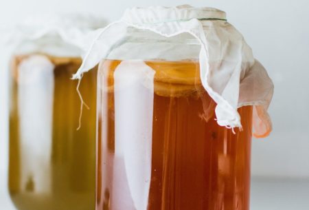View Kombucha: health panacea or just another fad? Two jars with kombucha covered in muslin cloth