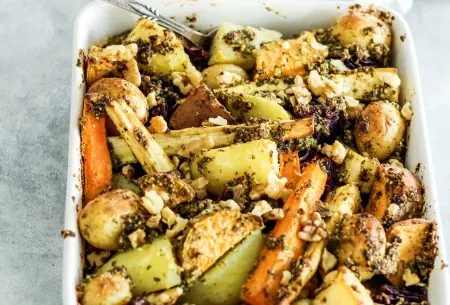 Large oven baking dish full with roasted potatoes and parsnips, mixed with walnut pesto