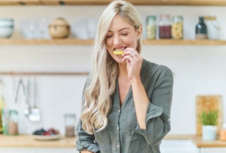 View Lemon water… magic or myth? Megan Rossi in kitchen slicing a lemon and eating it