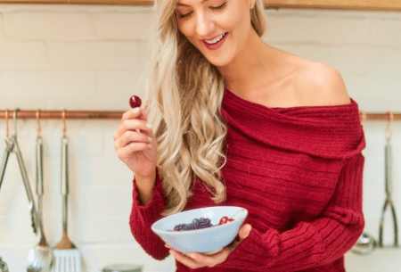 Megan Rossi sitting on the work surface eating a bowl of cherries and berries