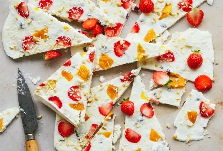 One large frozen live yoghurt bark, broken roughly into 12 pieces on a grey bench top