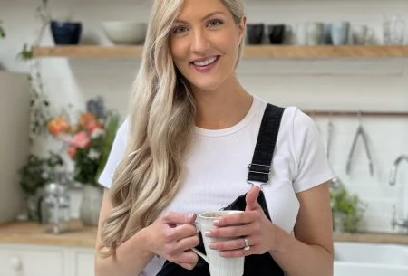 Dr Megan Rossi standing in a kitchen holding a ceramic mug between her hands