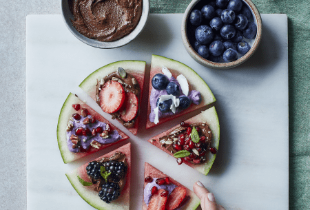 Six slices of watermelon displayed on a plate in a circle, stacked with fresh fruits