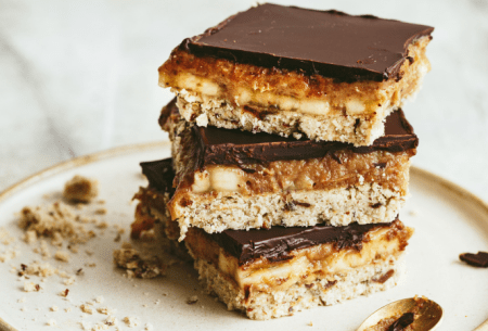 Three pieces of Banoffee millionaire shortbread stacked on a white plate