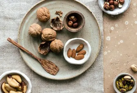Ceramic plate on benchtop with natural linen cloth underneath and assortment of nuts and seeds