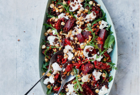 Colourful beetroot, lentil and goat’s cheese salad shown in a long serving dish with two serving spoons