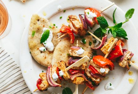 Two spiced tofu skewers with mint yoghurt, shown on white plate with torn flatbread