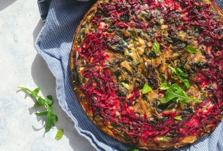 Fresh cooked full moreish spiced beetroot tart on bench with blue serving towel