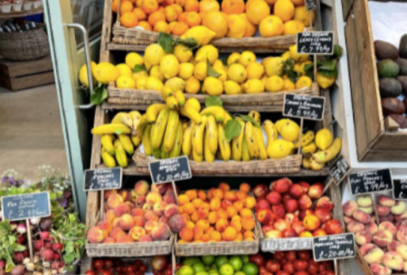 Market-style fruit stall stacked with six levels of overflowing mixed fruits and vegetables