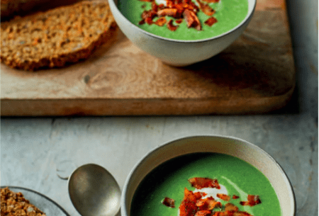 Two bowls of super green pea and ‘ham’ soup, with fresh bread on a chopping board