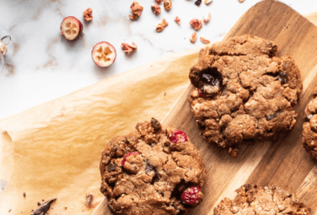 Three spiced cranberry and dark chocolate granola cookies displayed on a chopping board