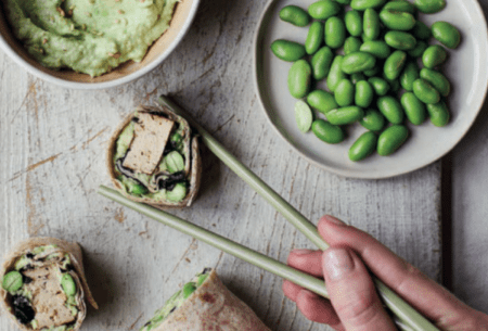 One fibre-filled breakfast wrap cut into sushi pieces. Displayed with chopsticks, extra edamame beans and homemade spread