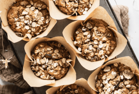 Six freshly baked gingerbread muffins in a muffin tray, sprinkled with granola