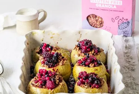 A white oven dish containing 6 super berry stuffed and baked apples