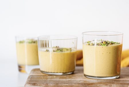 Three pots of gut-loving mango pudding, topped with chopped pistachios