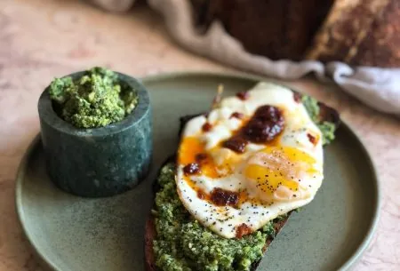 Pot of walnut and brussels sprout pesto with fried egg on sourdough toast