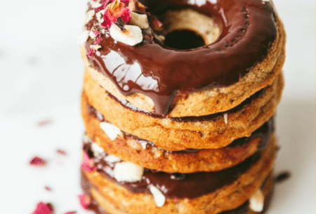 A stack of chocolate breakfast donuts sprinkled with rose petals and hazelnuts