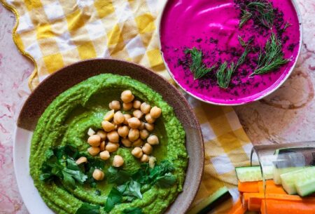 Photo of gut health friendly summer dips green hummus and beetroot dip on a table with vegetable sticks