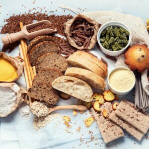 Photo of a spread of wholegrains and healthy food on a table including brown bread and wholegrain crackers to dispel diet myth of avoiding carbs and gluten 