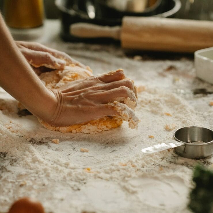 Photo of a someone kneading dough on a table covered in flour and a rolling pin in the background to reflect diet myth of homecooked food is better for you