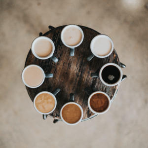 Photo looking down on a tray of 8 mugs of tea, ranging from very milky/white to very dark