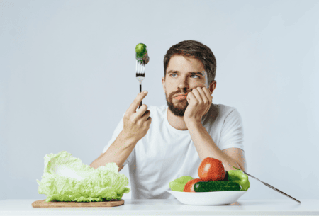 Photo of a man struggling to eat a Brussels sprout