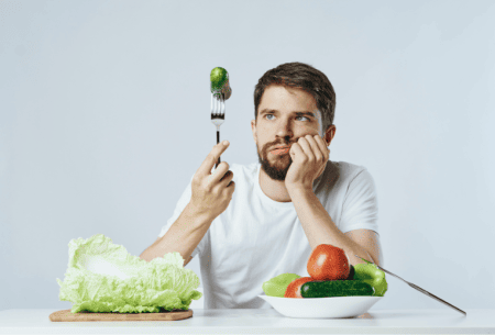 View Crohn’s disease dietary strategies and scientific support Photo of a man struggling to eat a Brussels sprout