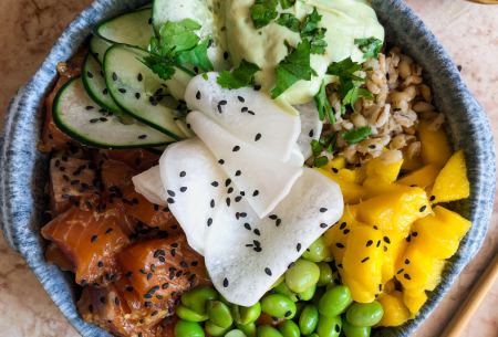 Photo of a poke bowl in a ceramic bowl with super six ingredients including edamame beans, mango and salmon