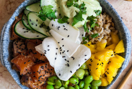 Photo of a poke bowl in a ceramic bowl with super six ingredients including edamame beans, mango and salmon