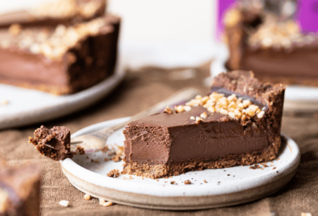 Photo of the bio&Me hazelnut and chocolate tart with one slice on a white plate with a forkful of tart next to it and Bio&Me packaging in the background