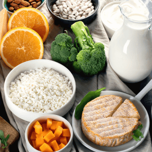 Photo of a platter of calcium-rich foods, including a jug of milk, broccoli and cheese