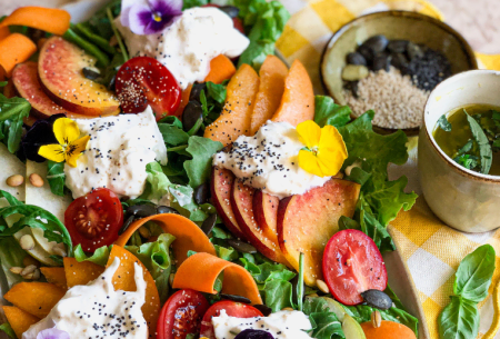 Photo of a vibrant end of summer salad including tomatoes, burrata, peaches, pears, seeds, rocket and other super six plant group ingredients