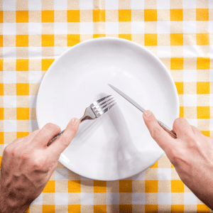 Photo of someone eating off an empty white plate and a yellow tablecloth in the background