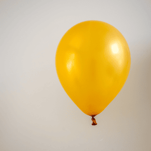 Photo of a blown up yellow balloon with a grey backdrop to reflect bloating