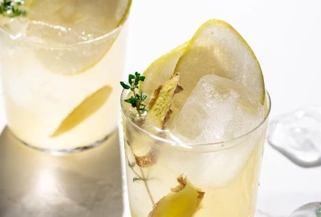 A glass of the pear & ginger spritz garnished with pear and thyme