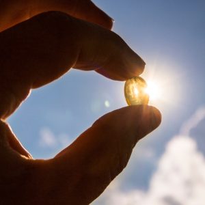 A photo of someone holding up vitamin D towards the sun