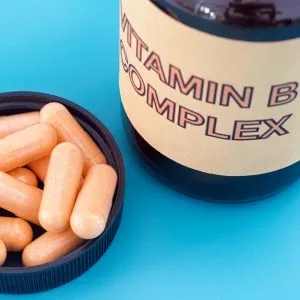 A photo of vitamin b pills in a bowl next to their jar which reads 'vitamin b complex'