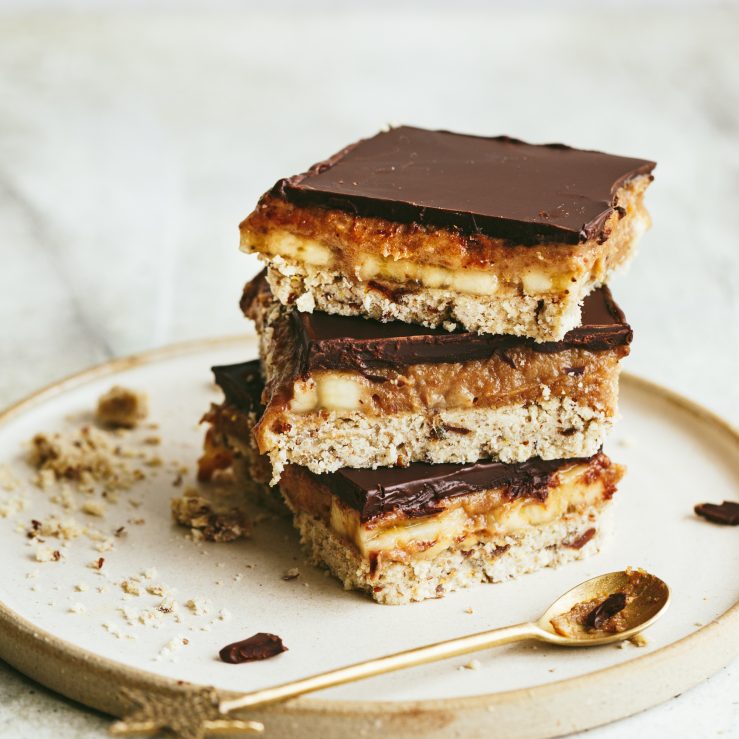 Three pieces of Banoffee millionaire shortbread stacked on a white plate