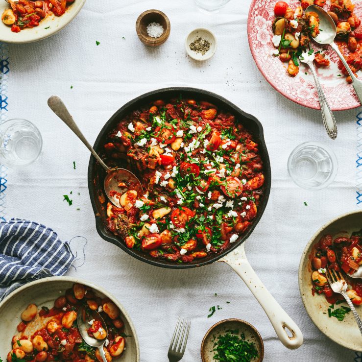 Gut-friendly Greek baked beans in a pan on a white table