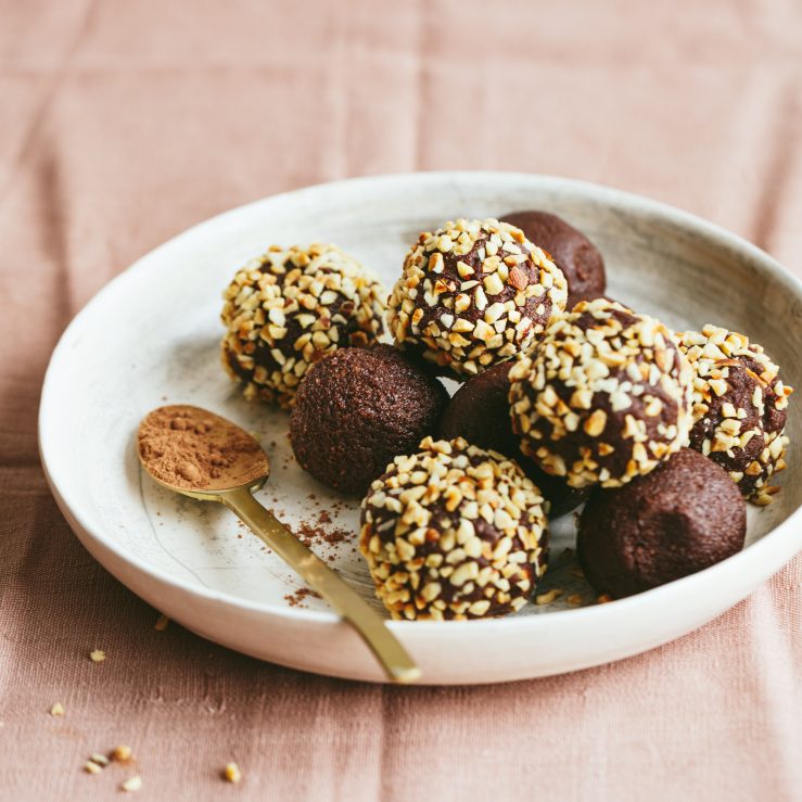 A plate of chocolate truffles some covered in chopped nuts