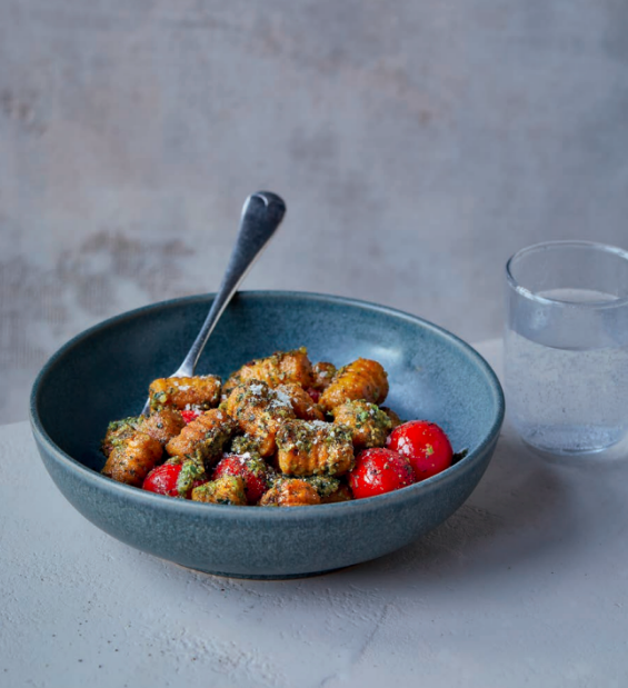 A blue bowl of sweet potato gnocchi covered in super pesto