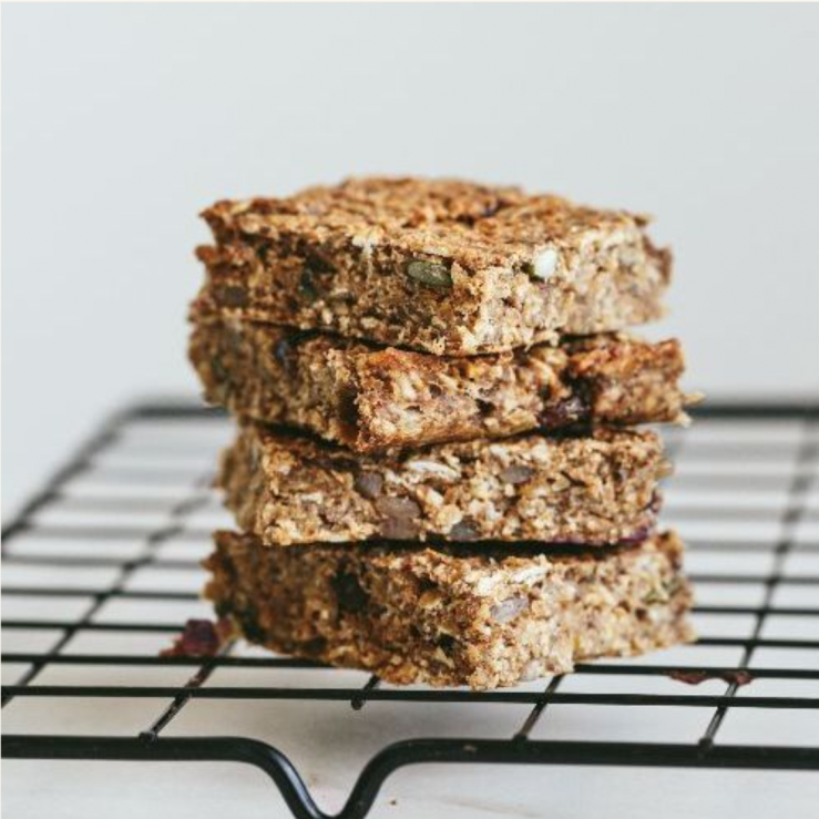 A stack of 4 nutty banana fibre-filled flapjacks balanced on a metal cooling rack
