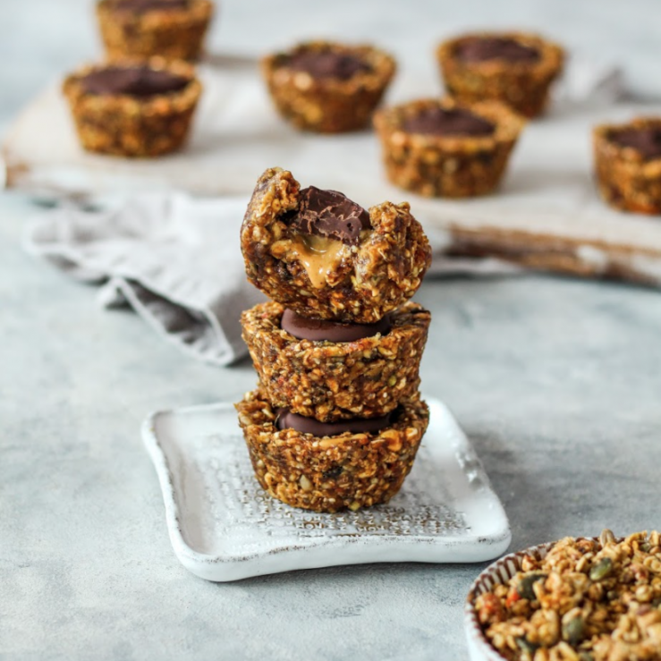 A stack of dark chocolate and peanut butter granola cups on small white rustic plate