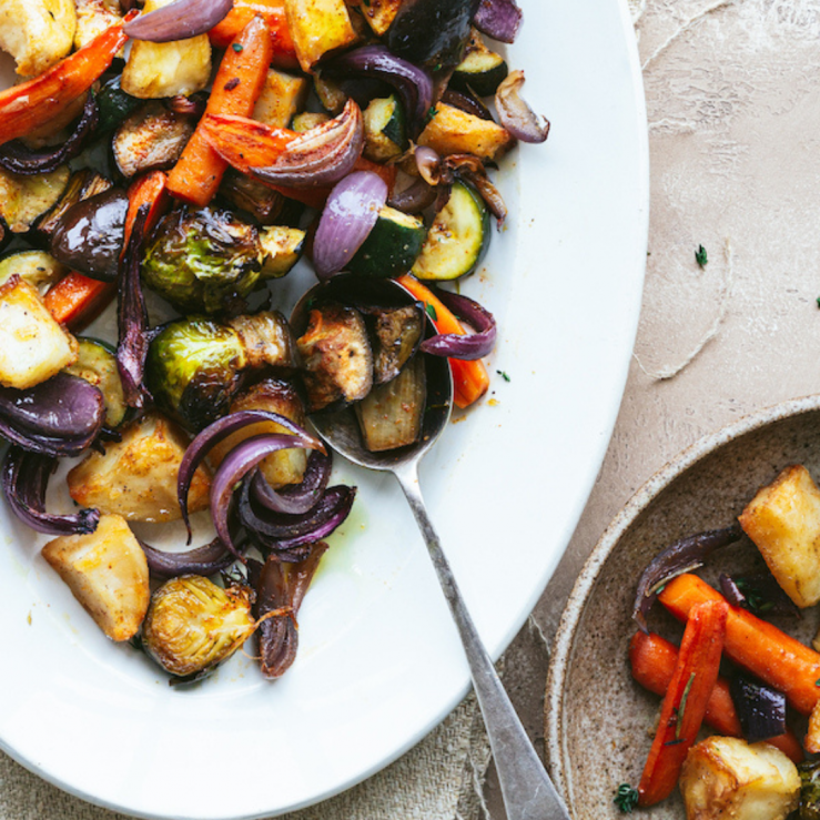 A large white serving plate of roasted vegetables