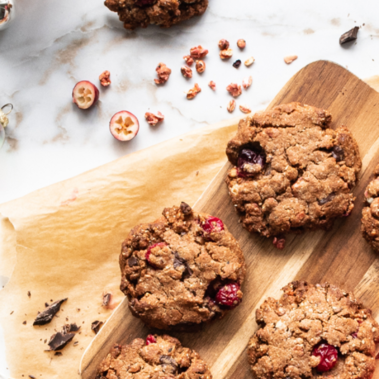 Three spiced cranberry and dark chocolate granola cookies displayed on a chopping board