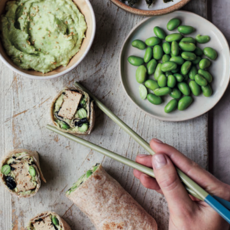 One fibre-filled breakfast wrap cut into sushi pieces. Displayed with chopsticks, extra edamame beans and homemade spread